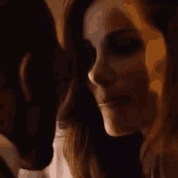 a man and a woman are kissing in a dark room in a close up of their faces .