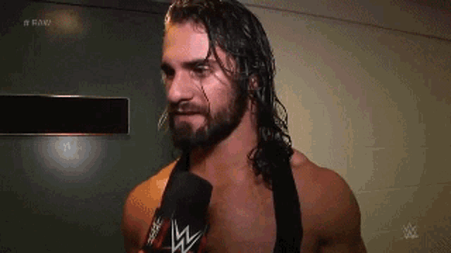 a man with long hair and a beard is holding a microphone in his hand .
