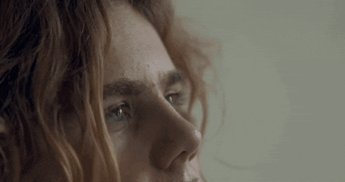a close up of a person 's face with red hair and blue eyes