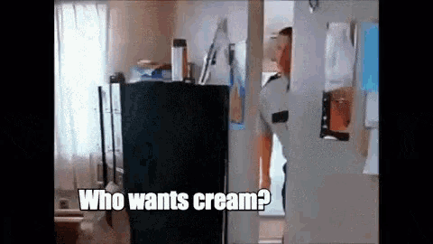 a man is standing in a doorway asking who wants cream .