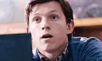 a young man is sitting at a table looking at a laptop computer .