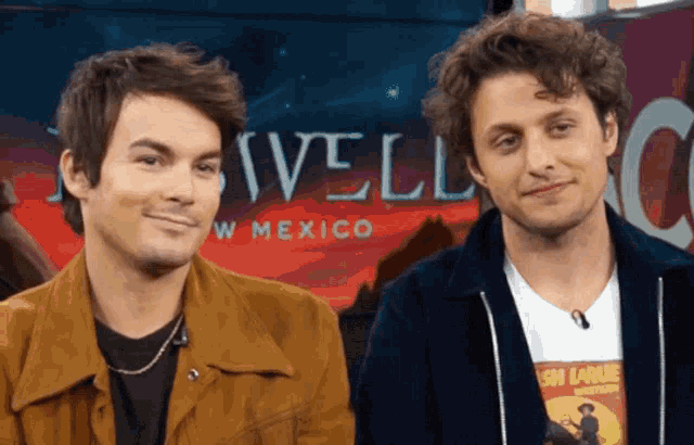two men are standing in front of a sign that says nivel w mexico