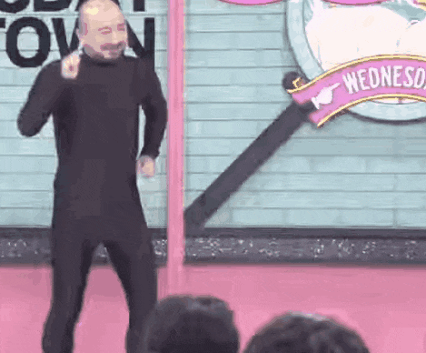 a man in a black suit is dancing on stage in front of a crowd .