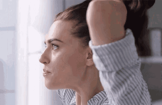 a woman in a striped shirt is holding her hair in a ponytail