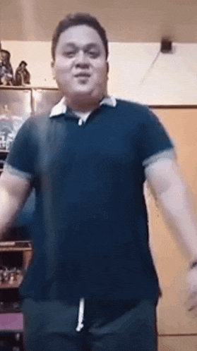 a man in a blue polo shirt is dancing in a room .
