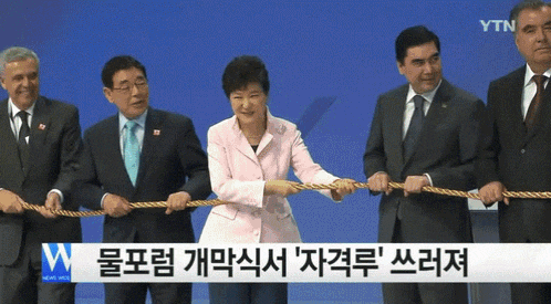 a group of men and a woman are pulling a rope in front of a sign that says ytn news web