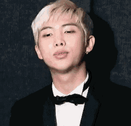 a young man wearing a tuxedo and bow tie is looking at the camera .