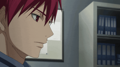 a man with red hair is standing in front of a shelf with blue binders