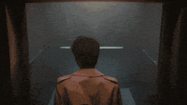 a man in a trench coat is standing in a dark room