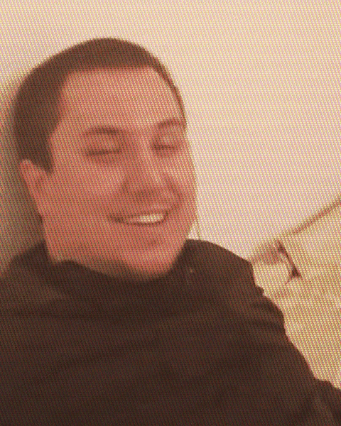 a man is smiling with his eyes closed in a blurry photo