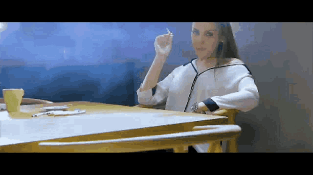 a woman sits at a table with a cup of coffee and a pen in her hand