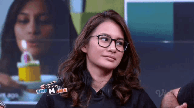 a woman wearing glasses and a shirt that says sinemania on it