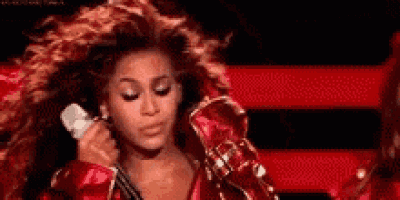 a woman in a red jacket is holding a microphone and singing into it .