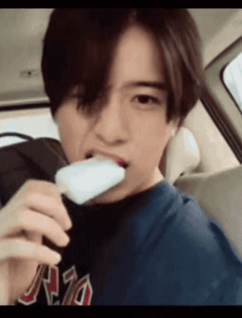 a young man is eating a popsicle in a car while wearing a rio shirt
