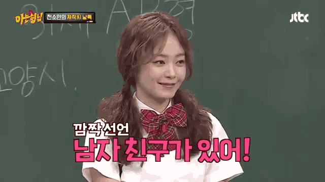a girl in a school uniform is talking in front of a chalkboard with korean writing on it