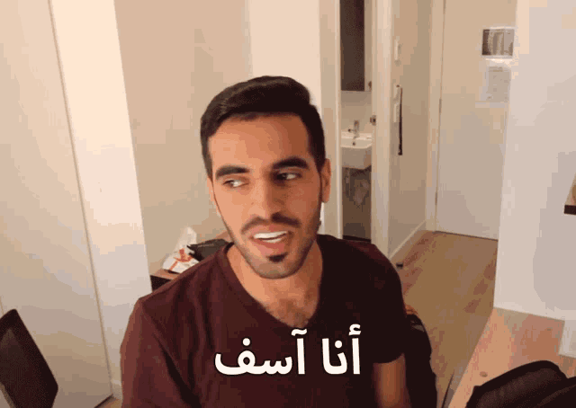 a man wearing a maroon shirt with arabic writing on the front