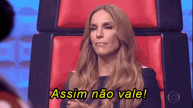 a woman is sitting in a red chair and says assim não vale