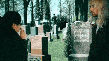 a man wipes his nose in front of a gravestone that says " martin "