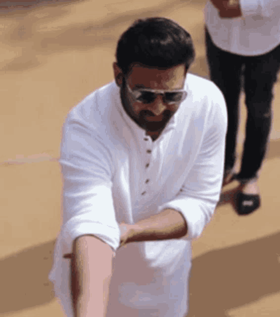 a man wearing sunglasses and a white shirt is standing on the ground