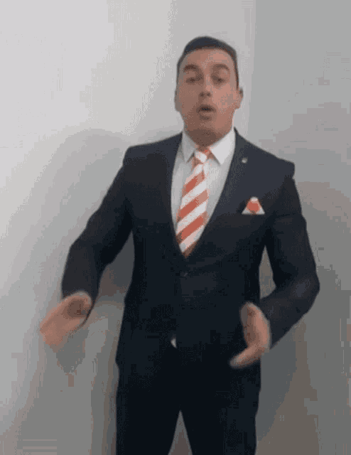 a man in a suit and tie is making a gesture with his hands
