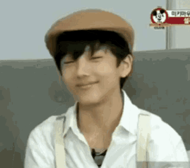 a young boy wearing a hat and suspenders is sitting on a couch .