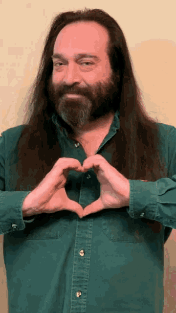 a man with long hair making a heart shape with his hands