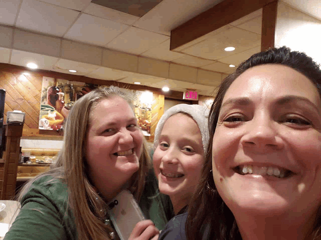 three women are posing for a picture in a restaurant with an exit sign in the background