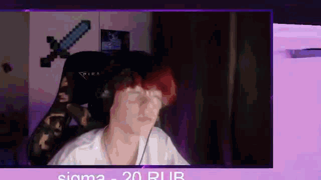 a man with red hair is sitting in a chair in front of a computer monitor .