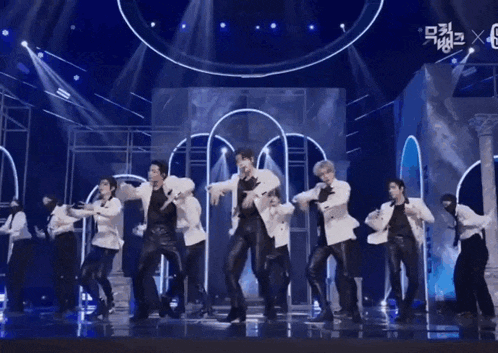 a group of men are dancing on a stage with a blue background .