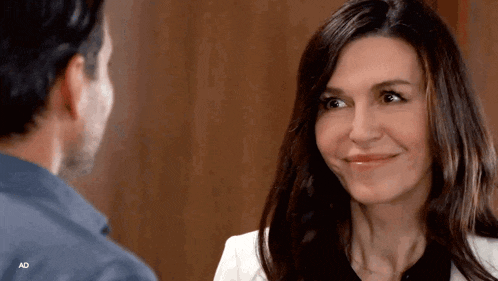 a man and a woman are looking at each other and the woman is smiling for the camera