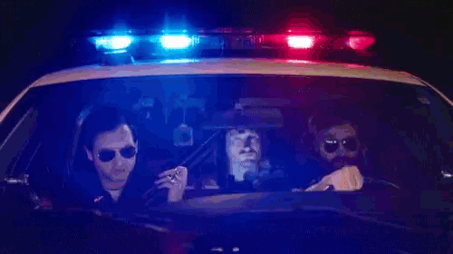 a group of people are sitting in a police car under a blue and red light