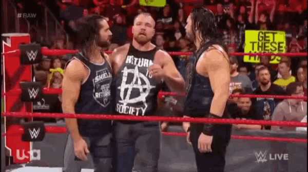 a group of wrestlers are standing in a wrestling ring talking to each other .