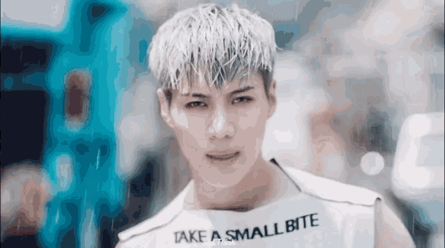 a young man is wearing a white tank top that says take a small bite