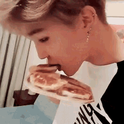 a close up of a person eating a sandwich with their mouth open .