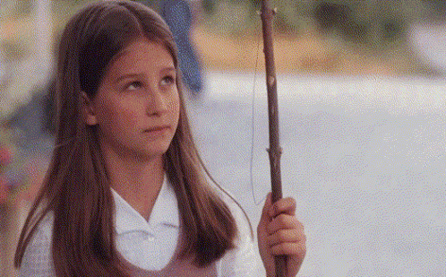 a young girl is holding a stick in her right hand