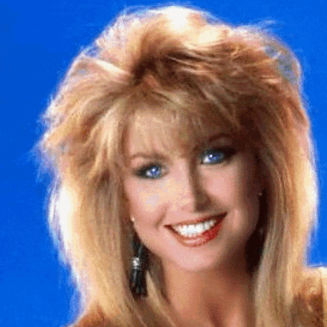 a woman with blonde hair and blue eyes smiles at the camera