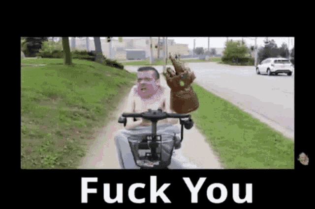 a man is riding a scooter with a glove on his head and the words `` fuck you '' below him .