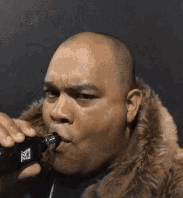 a man with a fur coat is smoking an electronic cigarette