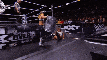 a female wrestler is kicking a trash can in a wrestling ring that says nxt