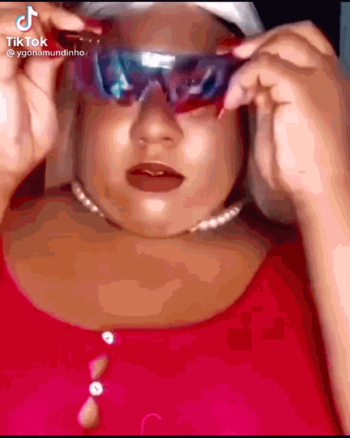 a woman is wearing a pair of sunglasses and a red shirt