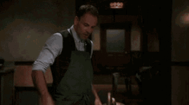a man in an apron is holding a piece of meat in his hands .