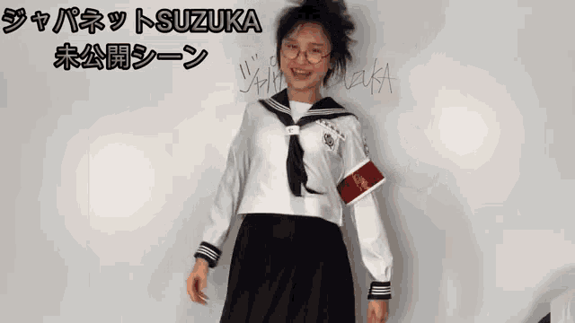 a girl in a sailor uniform is standing in front of a white board with chinese writing on it