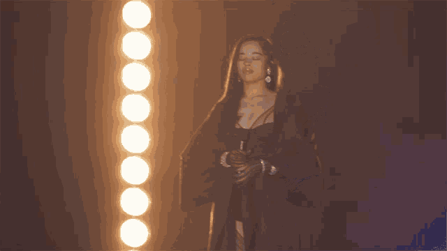 a woman stands in front of a row of lights in a dark room