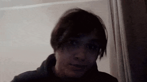 a man with short hair is making a funny face while looking at the camera in a dark room .