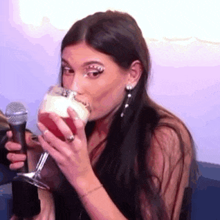 a woman is drinking from a glass while holding a microphone .