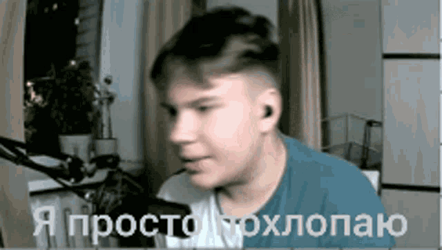 a man in a blue shirt is talking into a microphone while wearing earbuds .