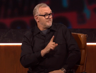 a man wearing glasses and a black shirt sitting in a chair
