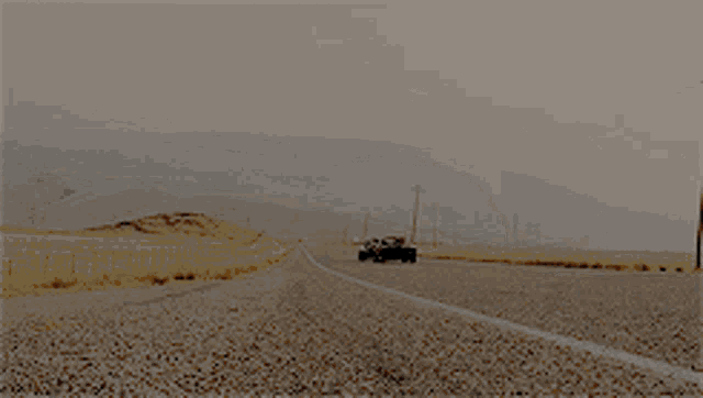 a black car is driving down a road with smoke coming out of the back