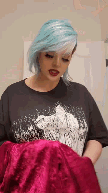 a woman with blue hair is wearing a t-shirt with a skeleton on it