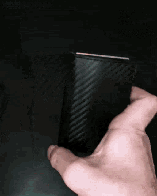 a person 's hand is holding a black wallet